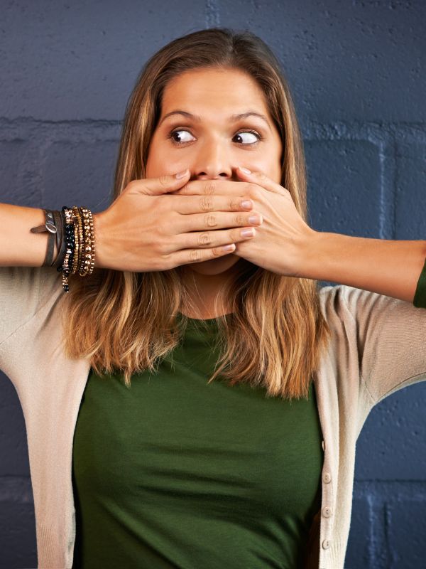 Woman holding her hands over her face looking to the side