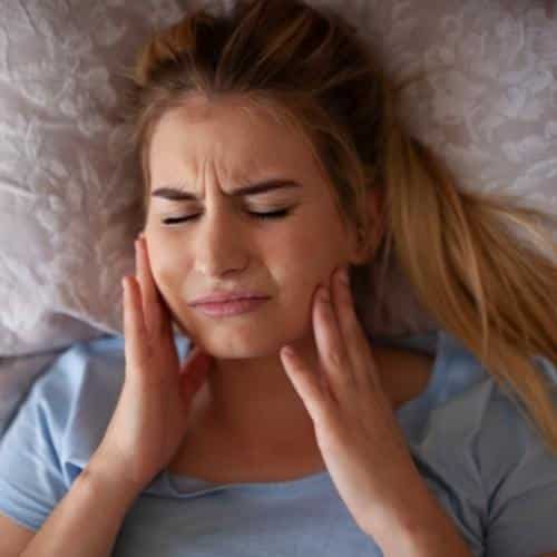 Woman holding jaws from aching teeth